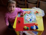 dvouletá dcerka lepí plastelínku na zalaminované obrázky